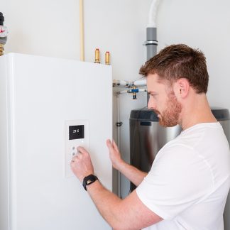 Maalämpöpumppujen huolto- ja korjauskoulutus. Kuvassa mies säätää laitteita.